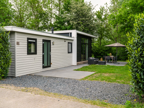 Lodge moderne River Cabin met bubbeltub avec coin salon extérieur, terrasse et arbres verdoyants autour.