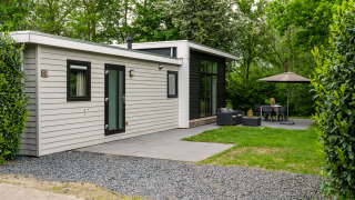 Lodge moderne River Cabin met bubbeltub avec coin salon extérieur, terrasse et arbres verdoyants autour.