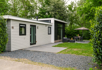 Moderne River Cabin met bubbeltub-lodge med udendørs siddeområde og have omgivet af grønne træer.