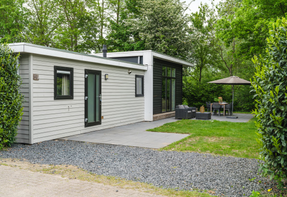 Cabaña moderna River Cabin met bubbeltub con terraza, muebles de jardín y rodeada de árboles verdes.