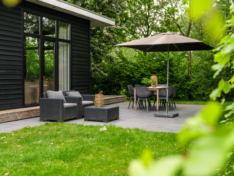 Terrasse extérieure avec fauteuils, table à manger et parasol à River Cabin, Holiday Park Mölke aux Pays-Bas.