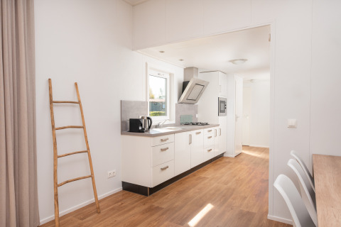 Lyst køkkenområde i River Cabin met bubbeltub ved Holiday Park Mölke, med trægulv og moderne faciliteter.