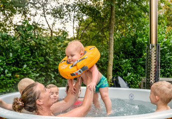Gezin geniet samen in een bubbelbad bij River Cabin met bubbeltub in Holiday Park Mölke, Nederland.