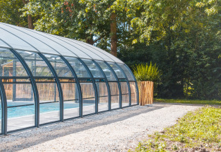 Covered swimming pool at Camping Seasonova du Chêne, surrounded by trees in Pays de la Loire, France.