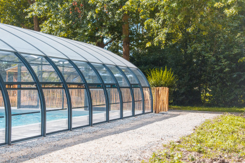 Piscina cubierta en Camping Seasonova du Chêne, rodeada de árboles en Pays de la Loire, Francia.
