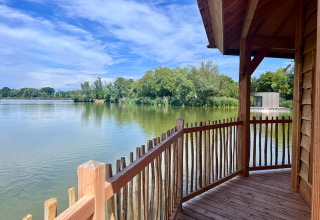 Blick von einer Holzveranda auf den See im Domaine des Feuilles, einem Ferienpark in Auvergne-Rhône-Alpes, Frankreich.