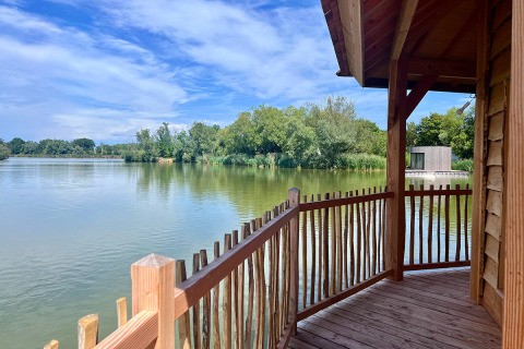 Vista desde el balcón de una cabaña de madera sobre el lago en Domaine des Feuilles, Auvernia-Ródano-Alpes, Francia.