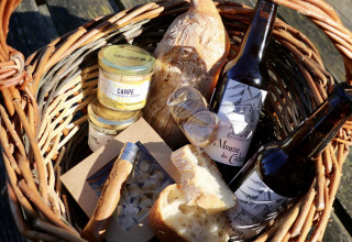 Picnickurv med brød, øl, marmelade, kniv og lækkerier fra Domaine des Feuilles i Auvergne-Rhône-Alpes.