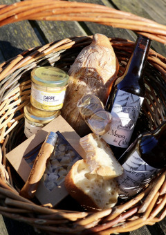 Panier de pique-nique avec pain, bières, tartinades et gourmandises de Domaine des Feuilles en Auvergne-Rhône-Alpes.