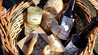 Panier de pique-nique avec pain, bières, tartinades et gourmandises de Domaine des Feuilles en Auvergne-Rhône-Alpes.