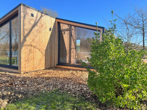 Cabane de vacances moderne en bois avec grandes fenêtres au Domaine des Feuilles, Auvergne-Rhône-Alpes.