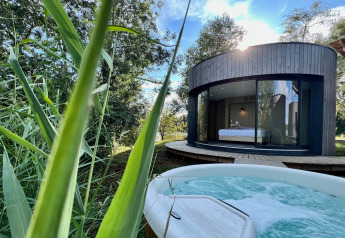 Buitenzicht op ronde Lumipod Spa île-hut met grote ramen en bubbelbad bij Domaine des Feuilles, Frankrijk.