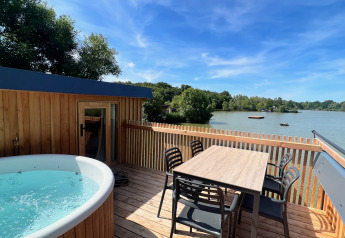 Terrazza all'aperto con vasca idromassaggio e tavolo da pranzo vista lago allo Spa Horizon Cabin, Domaine des Feuilles.