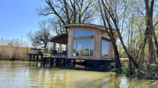 Cabina moderna in legno Spa Végétale sul lago con ampie finestre e terrazza attrezzata nel verde.