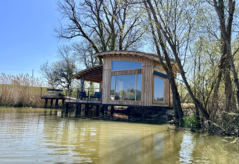 Cabina moderna in legno Spa Végétale sul lago con ampie finestre e terrazza attrezzata nel verde.