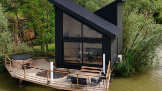 Spa Design Cabin, una cabina moderna dal tetto inclinato su una terrazza in legno che si affaccia sul lago.