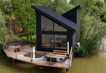Spa Design Cabin, una cabina moderna dal tetto inclinato su una terrazza in legno che si affaccia sul lago.