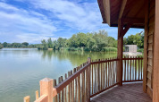 Vista dalla terrazza in legno di Cabine Ruche, Domaine des Feuilles, con lago e alberi in Francia.