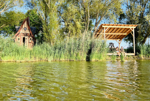 Sprookjesachtige hut en overdekt terras aan het water bij Cabine Fées, Domaine des Feuilles, Frankrijk.