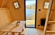 Interno in legno della lodge Cabine Fées al Domaine des Feuilles, Francia, con vista lago dalla porta.