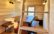 Interno di Cabine Boréalis con tavolo in legno, panche e scala al Domaine des Feuilles in Francia.
