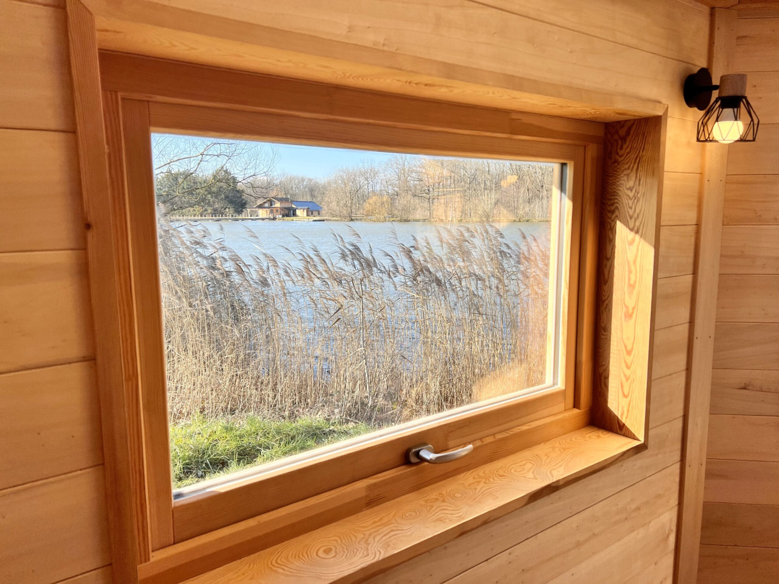 Uitzicht vanuit Cabine Boréalis in Domaine des Feuilles, Frankrijk, met raam op meer en natuur.