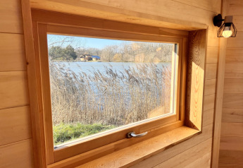 Vista dalla Cabine Boréalis presso Domaine des Feuilles in Francia: finestra che dà su un lago e alberi.