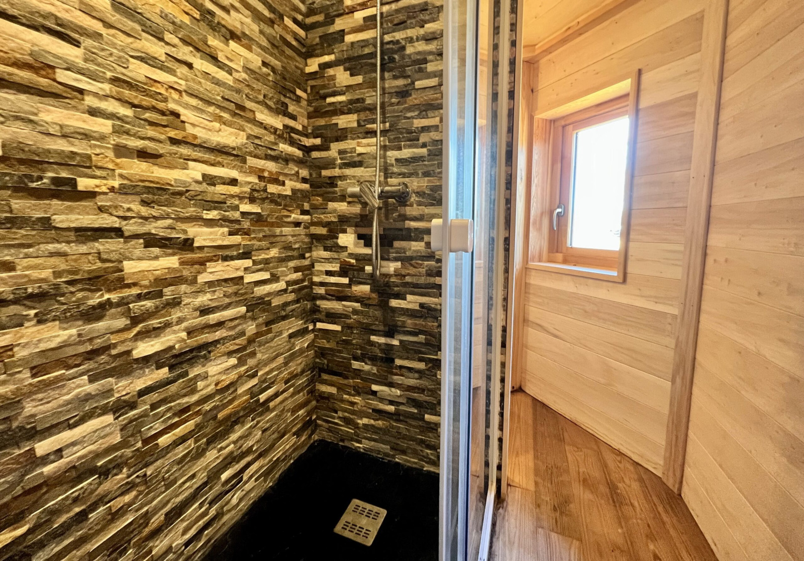 Douche met stenen tegels en glazen deur in Cabine Boréalis bij Domaine des Feuilles, Frankrijk.