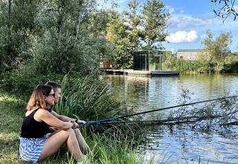 Twee mensen vissen aan het meer bij Cabine Spa Miroir op Domaine des Feuilles in Frankrijk, omgeven door natuur.