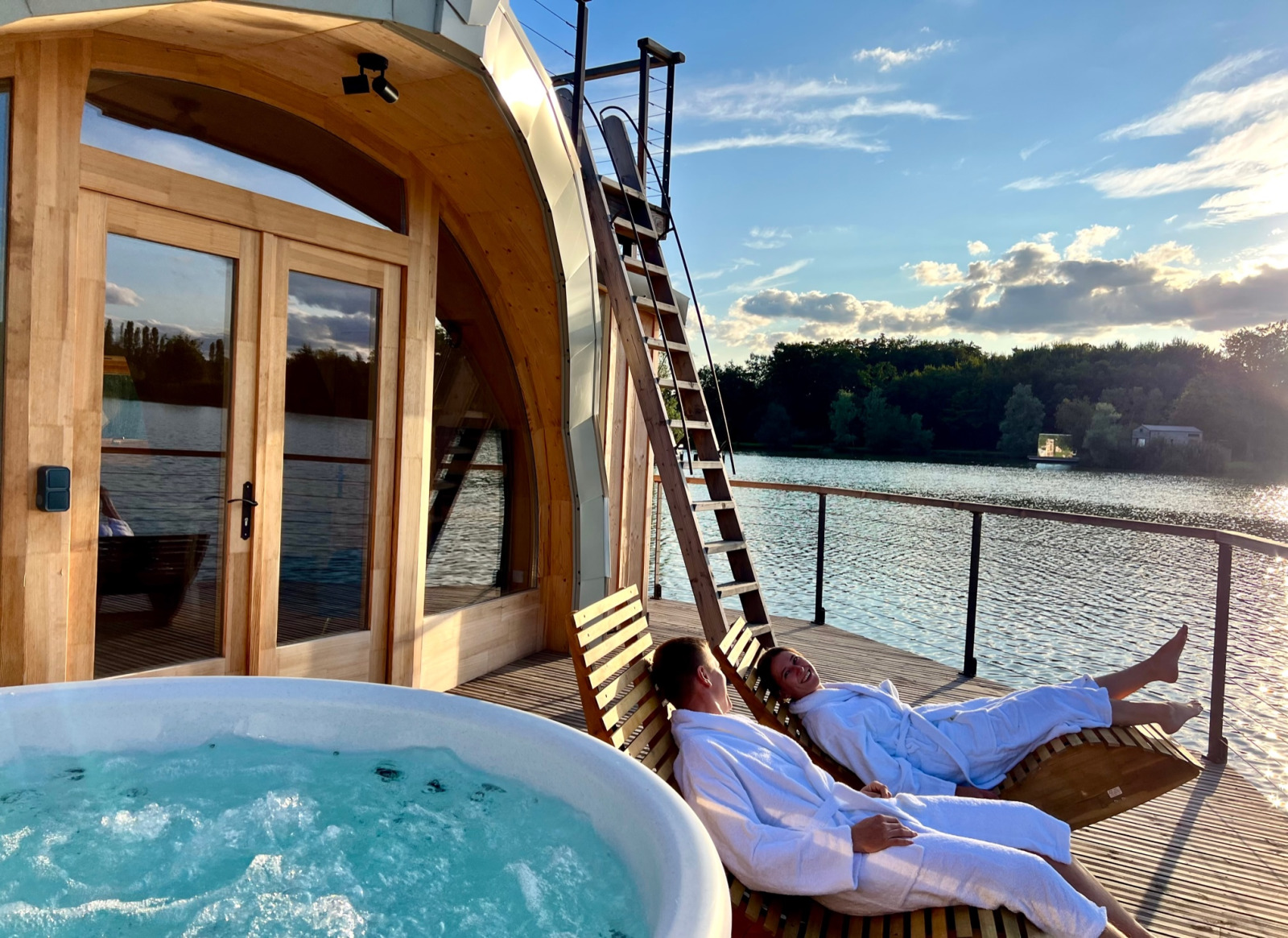 Twee mensen in badjassen ontspannen op ligstoelen bij een jacuzzi bij Cabine Spa Les Flots in Frankrijk.