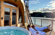 Due persone in accappatoio si rilassano su lettini presso una cabina con jacuzzi a Domaine des Feuilles, Francia.