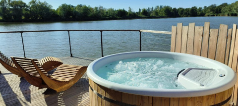 Buitenspa en houten ligzetels op terras met uitzicht op het meer bij Cabine Spa Les Flots, Domaine des Feuilles.