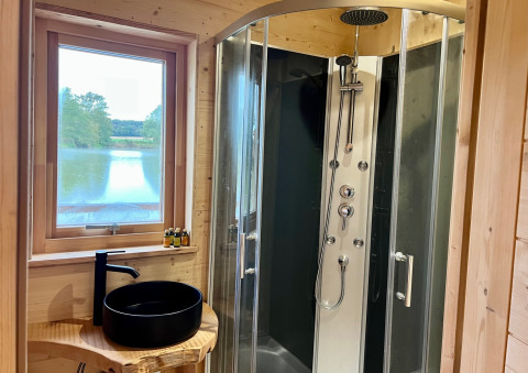Moderne badkamer in een houten cabin met douche, zwarte waskom en meerzicht bij Cabine Spa Les Flots.