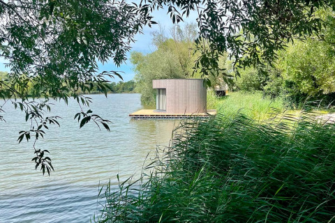 Ronde drijvende hut Lumipod Flottant bij Domaine des Feuilles in Frankrijk, omgeven door groen en water.
