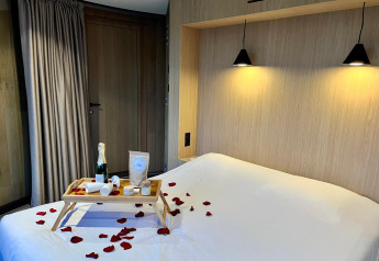 Camera romantica al Lumipod Flottant del Domaine des Feuilles, vassoio colazione e petali di rosa sul letto.