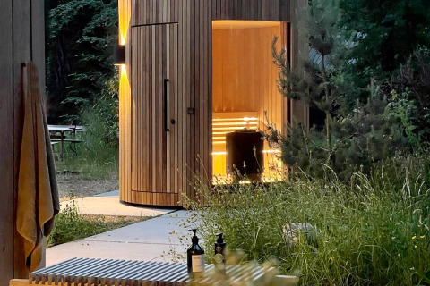 Houten Lumipod Spa île sauna bij Domaine des Feuilles in Frankrijk, genesteld tussen bomen en groen.