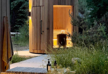 Houten Lumipod Spa île sauna bij Domaine des Feuilles in Frankrijk, genesteld tussen bomen en groen.