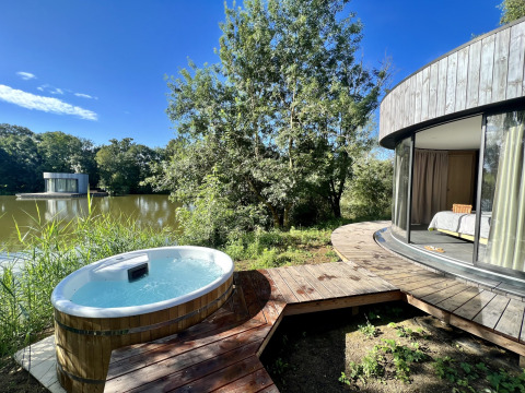 Bubbelbad buiten en ronde Lumipod cabana aan het meer op Domaine des Feuilles in Frankrijk, volle natuur rondom.