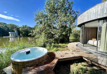 Bubbelbad buiten en ronde Lumipod cabana aan het meer op Domaine des Feuilles in Frankrijk, volle natuur rondom.