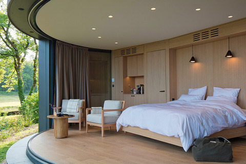 Moderne slaapkamer in Lumipod île bij Domaine des Feuilles, Frankrijk, met grote ramen en houten interieur.