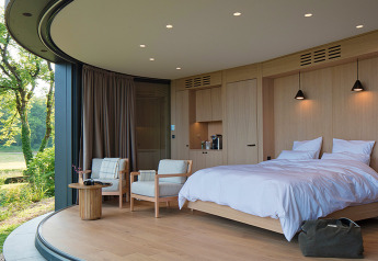 Moderne slaapkamer in Lumipod île bij Domaine des Feuilles, Frankrijk, met grote ramen en houten interieur.