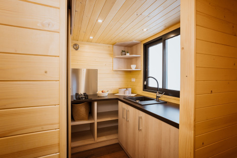Kompakte moderne Holzküche in einem Tiny House namens Klein huisje im Domaine des Feuilles, Frankreich.