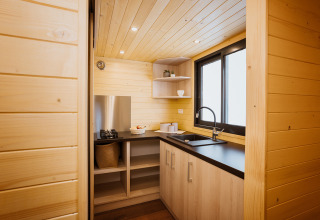 Kompakte moderne Holzküche in einem Tiny House namens Klein huisje im Domaine des Feuilles, Frankreich.