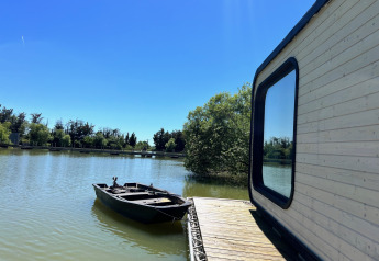 Héron Cabin am Domaine des Feuilles in Frankreich mit Blick auf den See und ein Boot am Steg.
