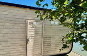 Cabina Héron presso Domaine des Feuilles in Francia, giornata di sole, rami di alberi e foglie verdi davanti.