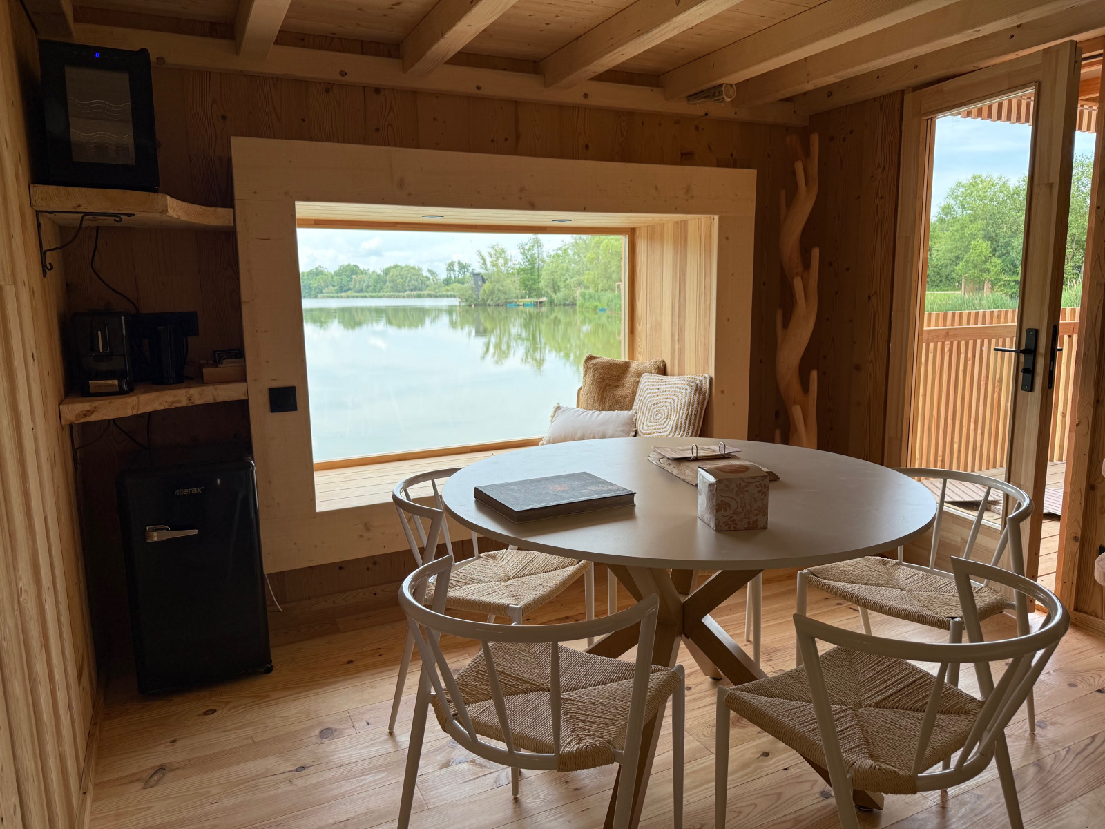 Spa Horizon Cabin bij Domaine des Feuilles in Frankrijk met houten interieur, uitzicht op meer en eettafel.