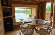 Spa Horizon Cabin al Domaine des Feuilles in Francia con interni in legno, vista lago e tavolo da pranzo.