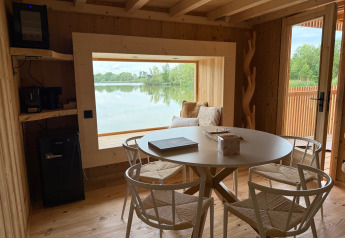 Spa Horizon Cabin al Domaine des Feuilles in Francia con interni in legno, vista lago e tavolo da pranzo.