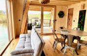 Interni della Spa Végétale Cabin al Domaine des Feuilles in Francia con pareti in legno, divano e tavolo.