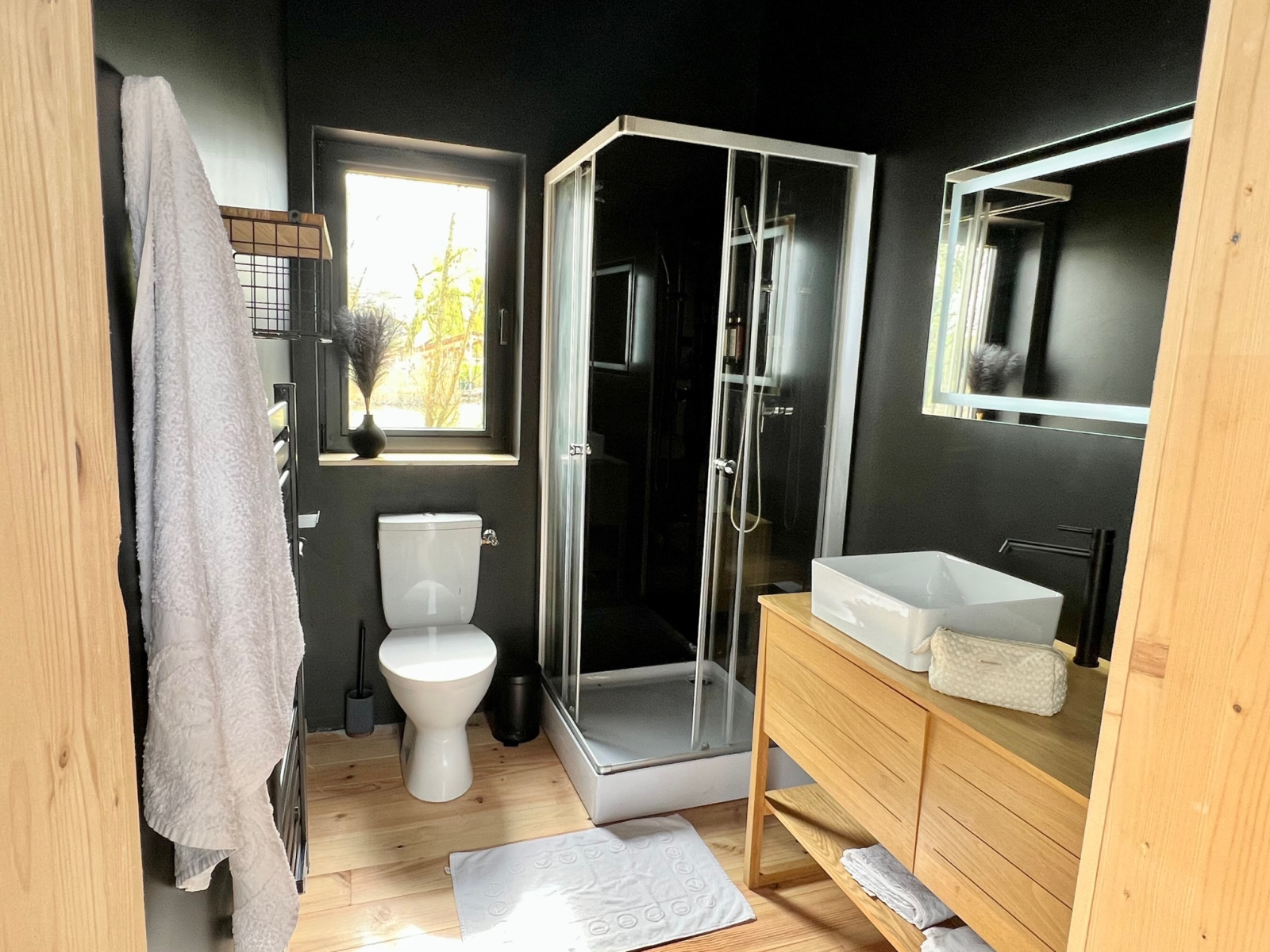 Moderne badkamer met douche, toilet en houten meubels in Spa Design Cabin bij Domaine des Feuilles, Frankrijk.